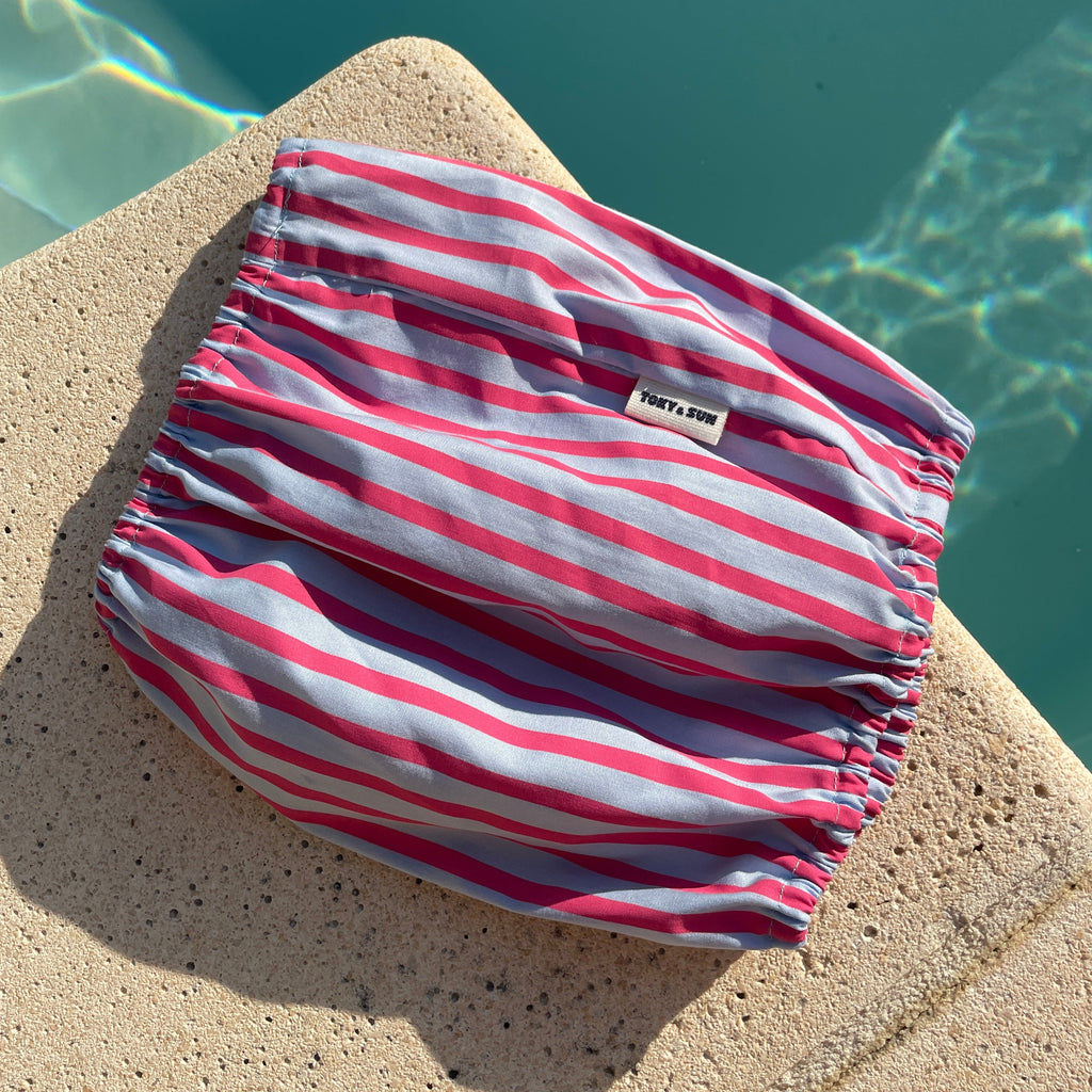 Snood rose et bleu rayé pour chien présenté au bord d'une piscine en été, marque TOKY AND SUN