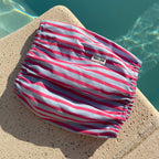 Snood rose et bleu rayé pour chien présenté au bord d'une piscine en été, marque TOKY AND SUN